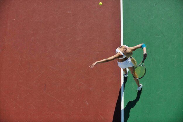 Młoda kobieta gra w tenisa na zewnątrz.