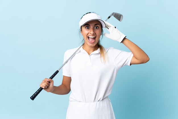Młoda kobieta hiszpanin golfista na pojedyncze niebieskie ściany z wyrazem zaskoczenia