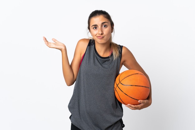 Młoda kobieta hiszpanin gra w koszykówkę na białym tle wątpliwości podczas podnoszenia rąk