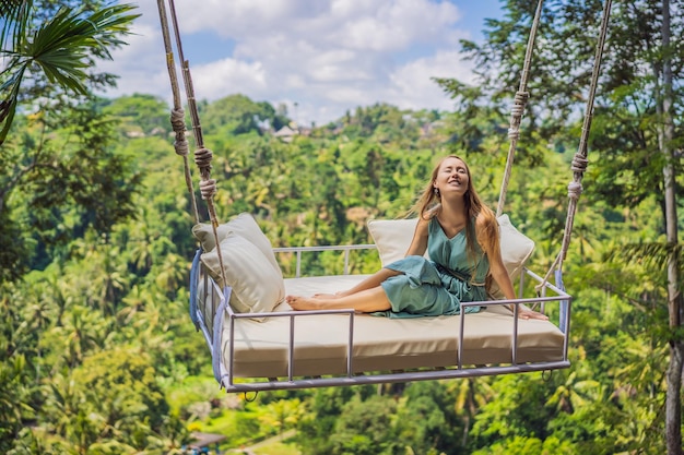 Młoda kobieta huśta się w dżungli na wyspie Bali Indonezja Huśtawka w tropikach Trend huśtawek na Bali