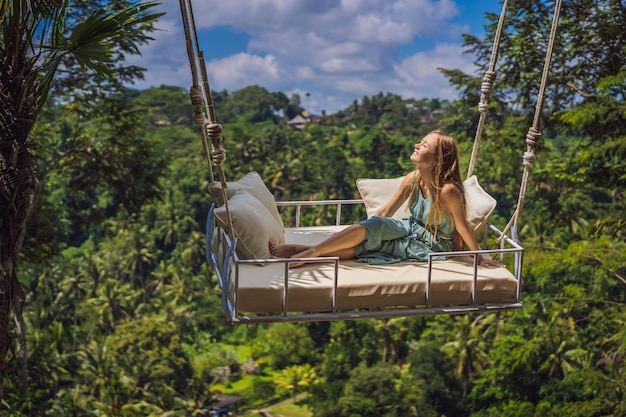 Młoda kobieta huśta się w dżungli na wyspie Bali Indonezja Huśtawka w tropikach Trend huśtawek na Bali