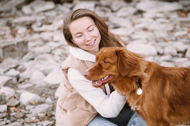 Zdjęcie młoda kobieta i pies retriever spacerują po brzegu rzeki w sezonie jesiennym