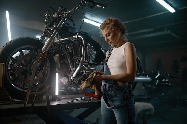 Zdjęcie młoda kobieta inżynier motocyklowy naprawiający rower w warsztacie wieczorem