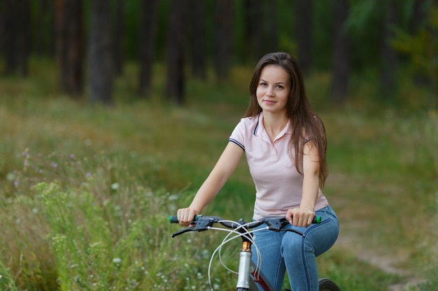 Młoda kobieta, jazda na rowerze w lesie. Wypoczynek na rowerze, aktywny tryb życia, jazda na rowerze w parku. ścieśniać
