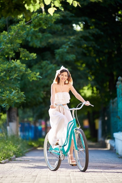 Młoda kobieta jedzie niebieski rower na zewnątrz