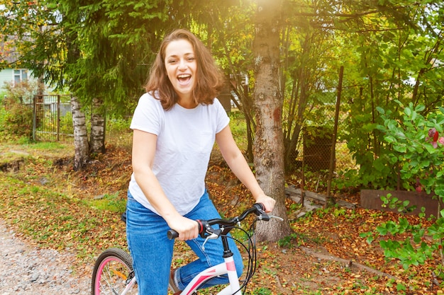 Młoda kobieta jeździecki bicykl w lata miasta parku outdoors. Aktywni ludzie. Hipster dziewczyna zrelaksować się i jeździć rowerem. Rowerem do pracy w letni dzień. Koncepcja stylu życia rower i ekologia.