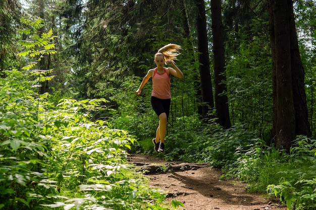 Młoda kobieta jogging na szlaku w górskim lesie