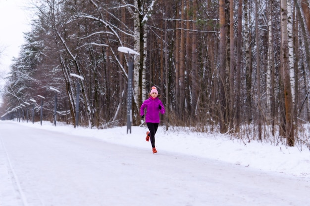 Młoda kobieta jogging na zaśnieżonej alejce w zimowy dzień