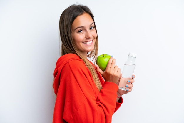Młoda kobieta kaukaska na białym tle na białym tle z jabłkiem i butelką wody