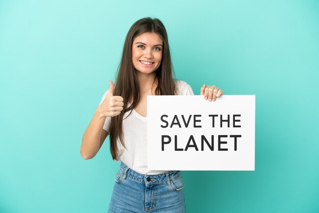 Młoda kobieta kaukaska na białym tle na niebieskim tle trzymając plakietkę z tekstem Save the Planet z kciukiem do góry