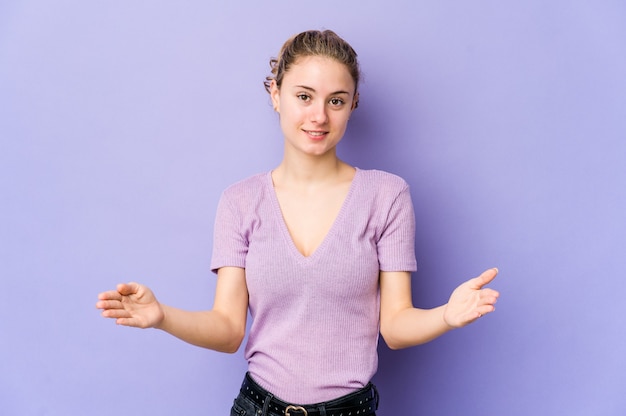 Młoda kobieta kaukaska na fioletowo pokazująca powitalną ekspresję