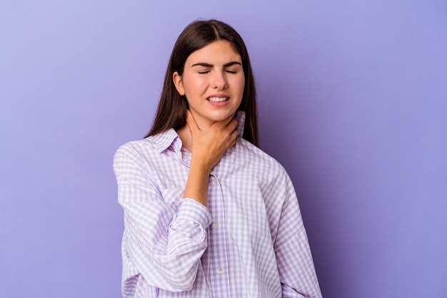 Młoda kobieta kaukaski na białym tle na fioletowym tle cierpi na ból gardła z powodu wirusa lub infekcji.