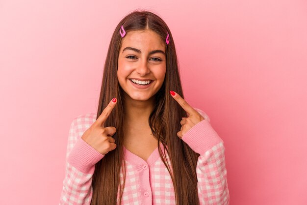 Młoda kobieta kaukaski na białym tle na różowym tle uśmiecha się, wskazując palcami na ustach.