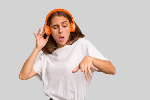 Młoda kobieta kaukaski, słuchanie muzyki w słuchawkach na białym tle