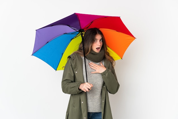 Młoda kobieta kaukaski trzymając parasol na białym tle zaskoczony i zszokowany, patrząc w prawo