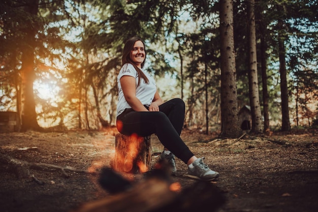 Młoda kobieta korzystająca z pikniku na łonie natury, spacerując po lesie, ciesząc się zachodem słońca