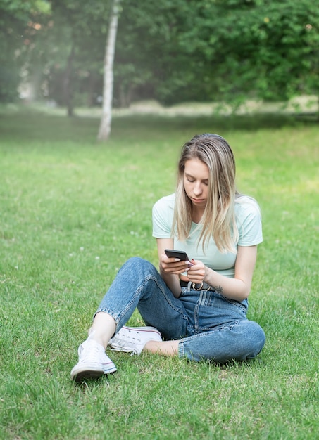 Młoda kobieta korzystająca ze smartfona w parku