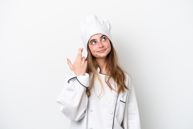 Młoda kobieta kucharz kaukaski na białym tle z palcami skrzyżowanymi i życzącymi wszystkiego najlepszego