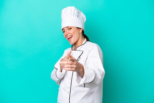 Młoda kobieta kucharz kaukaski odizolowana na niebieskim tle, skierowana do przodu i uśmiechnięta