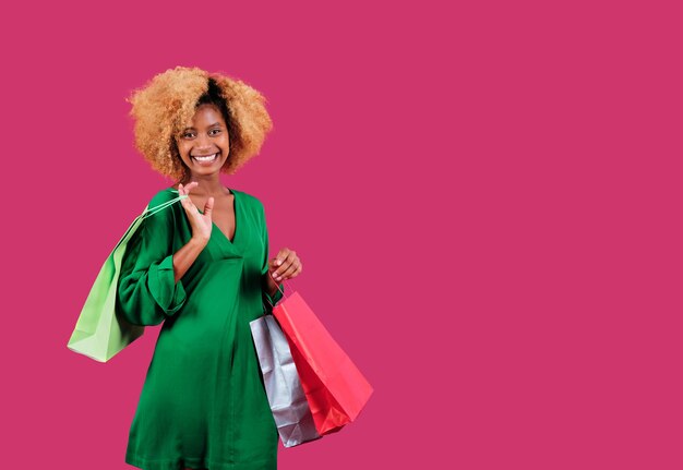 Młoda kobieta kupujący patrząc w kamerę i uśmiechając się trzymając kolorowe torby na zakupy na na białym tle. Koncepcja sprzedaży czarny piątek.