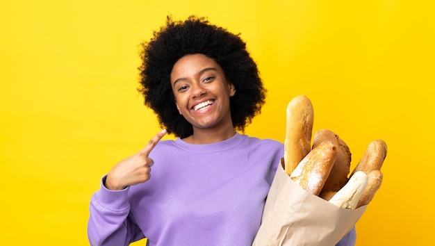 Młoda kobieta kupuje coś chleb odizolowywającego na kolorze żółtym daje aprobata gestowi
