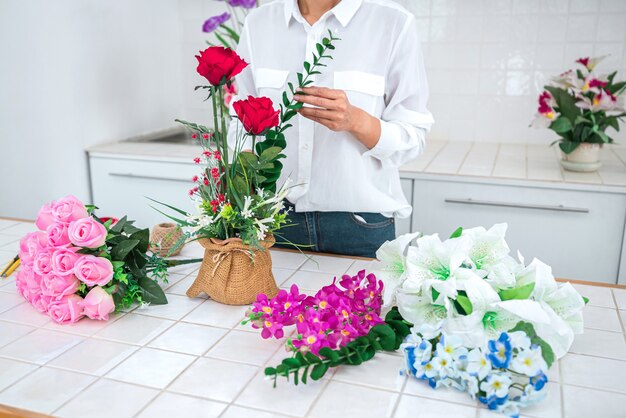 Zdjęcie młoda kobieta kwiaciarnia pracy, organizując diy sztuczny kwiat, rzemiosło i ręcznie robioną koncepcję.
