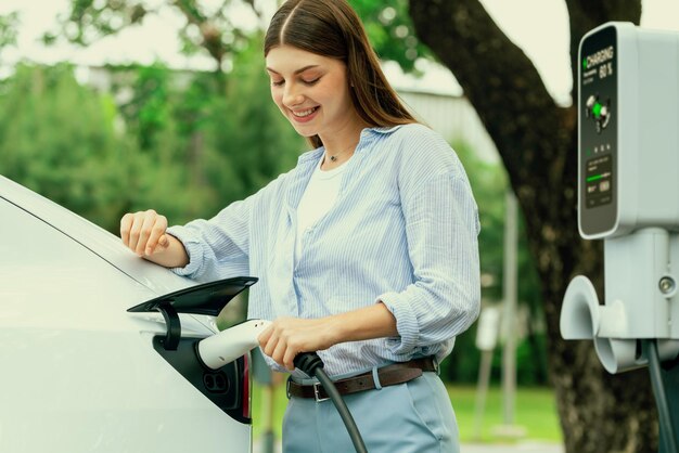 Zdjęcie młoda kobieta ładuje baterię pojazdu elektrycznego ze stacji ładowania elektrycznego exalt