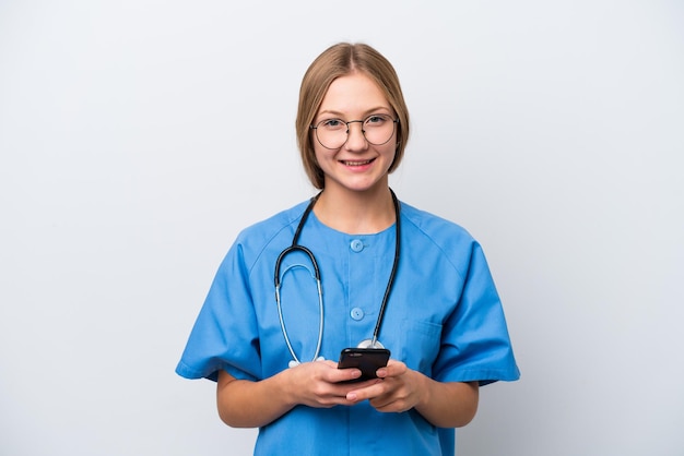 Młoda kobieta lekarz pielęgniarka na białym tle wysyłająca wiadomość za pomocą telefonu komórkowego