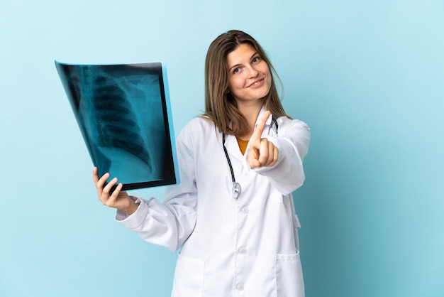 Młoda kobieta lekarz posiadający radiografię na białym tle pokazując i podnosząc palec