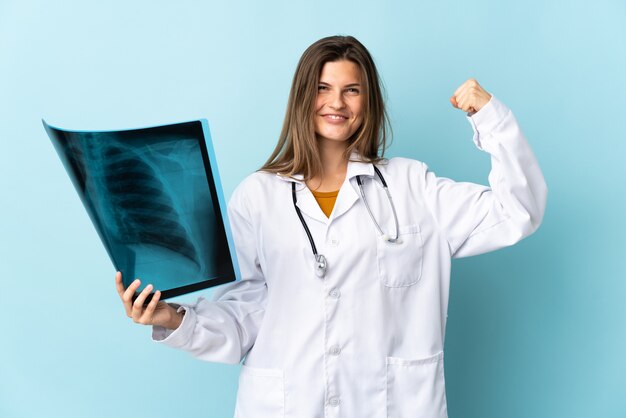 Młoda kobieta lekarz trzymając radiografię na białym tle robi silny gest