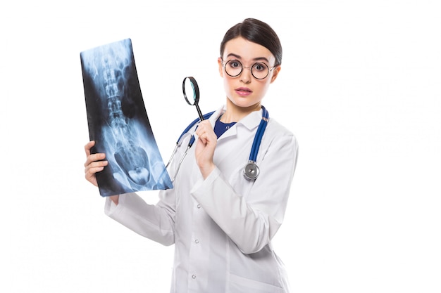Młoda kobieta lekarz z stetoskop patrząc na x-ray podejmowania diagnozy w białym mundurze na białym tle