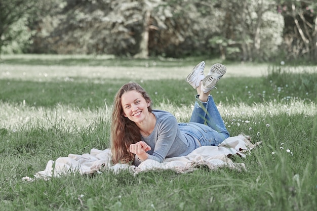 Młoda kobieta leżąc na trawniku w letni dzień