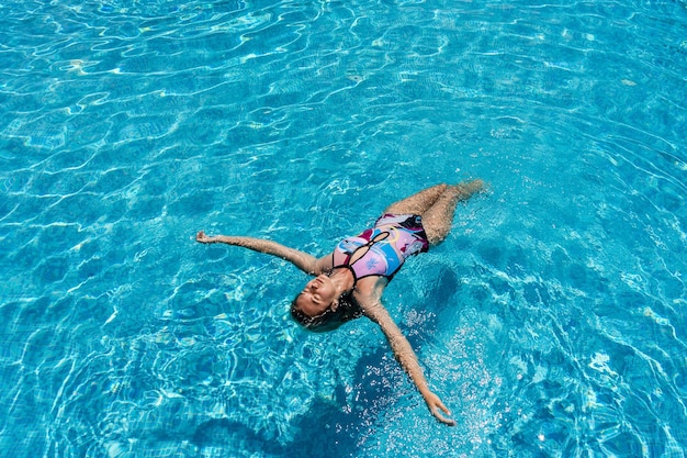 Młoda kobieta leży na powierzchni wody w kryształowym basenie