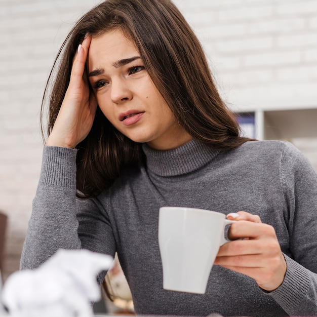 Młoda kobieta ma ból głowy podczas pracy w domu