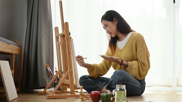 Zdjęcie młoda kobieta maluje na płótnie w domu