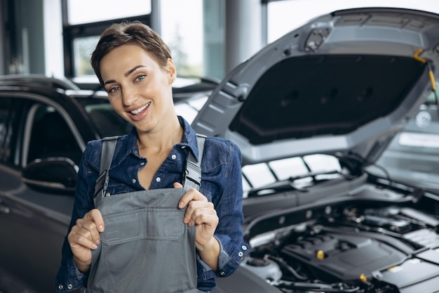 Młoda kobieta mechanik samochodowy sprawdzający samochód w serwisie samochodowym