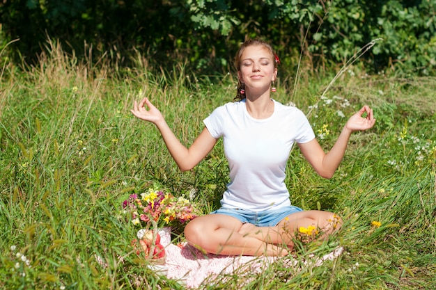 Młoda kobieta medytuje w pozycji lotosu