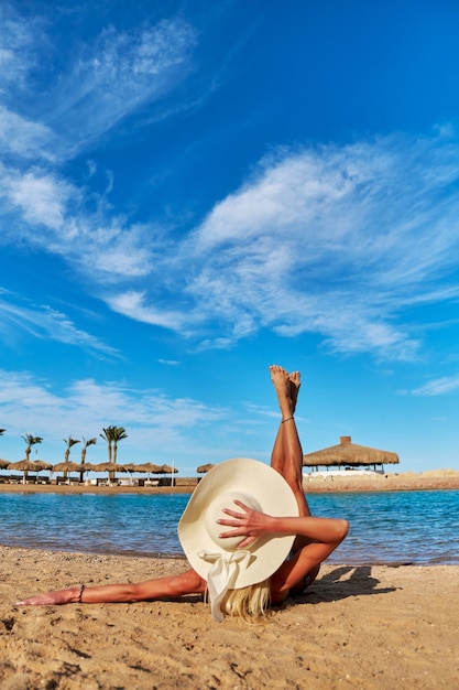 Zdjęcie młoda kobieta moda siedzi na brzegu plaży