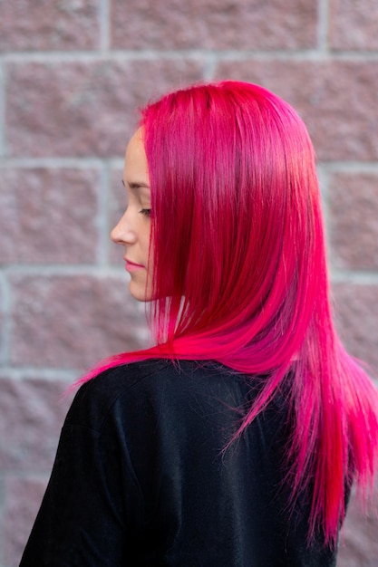 Młoda kobieta moda z różowe fryzury na tle cegły