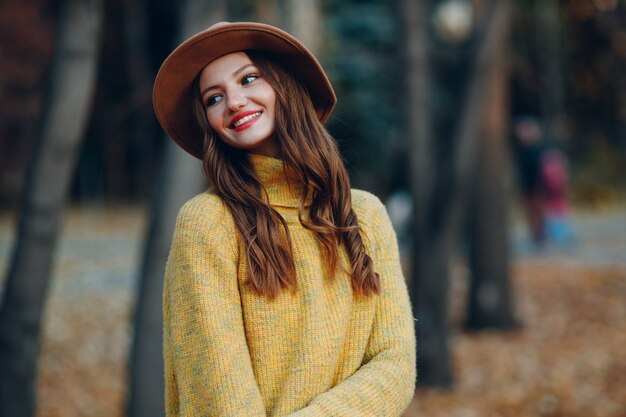 Młoda kobieta model w parku jesień z żółtymi liśćmi klonu. Jesienna moda.