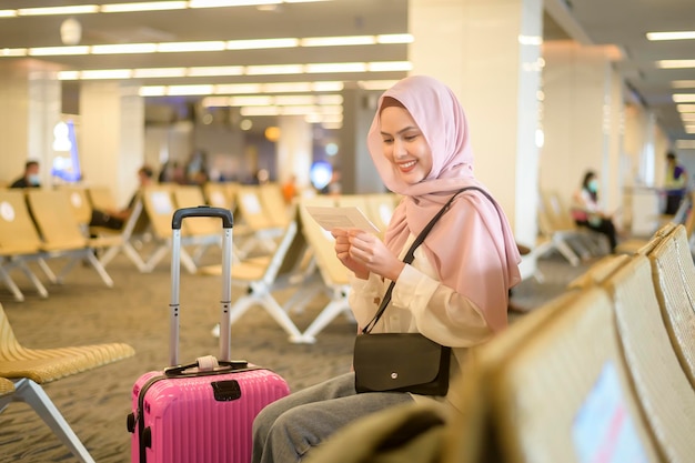 Młoda kobieta muzułmańska podróżniczka niosąca walizki na międzynarodowym lotnisku