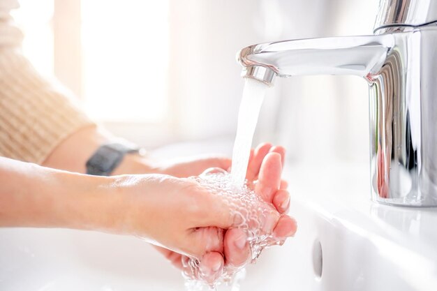 Młoda kobieta myje ręce mydłem nad zlewem