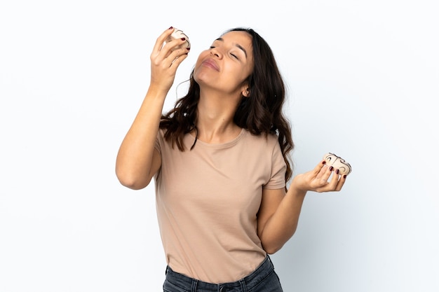 Młoda kobieta na białym tle trzymając pączki z zadowolonym wyrazem