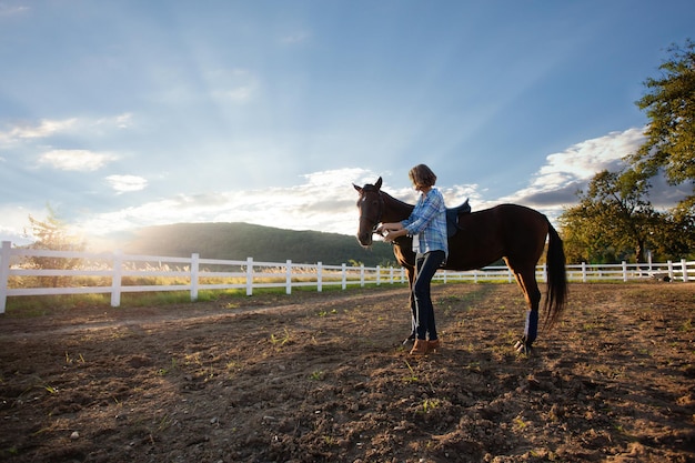 Młoda kobieta na koniu patrzy na zachód słońca