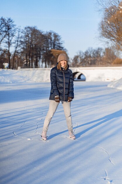 Młoda kobieta na łyżwach, sporty zimowe, śnieg, zimowa zabawa. Kobieta uczy się jeździć na łyżwach na jeziorze, natura, słoneczny dzień.