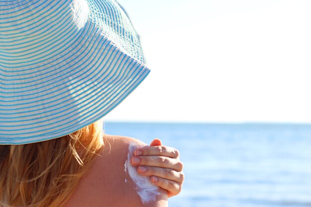 Zdjęcie młoda kobieta na plaży używa kremu przeciwsłonecznego