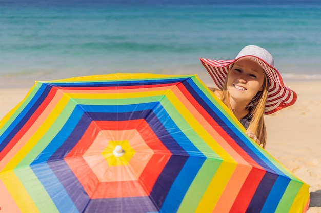 Młoda kobieta na plaży w kapeluszu i parasolu plażowym