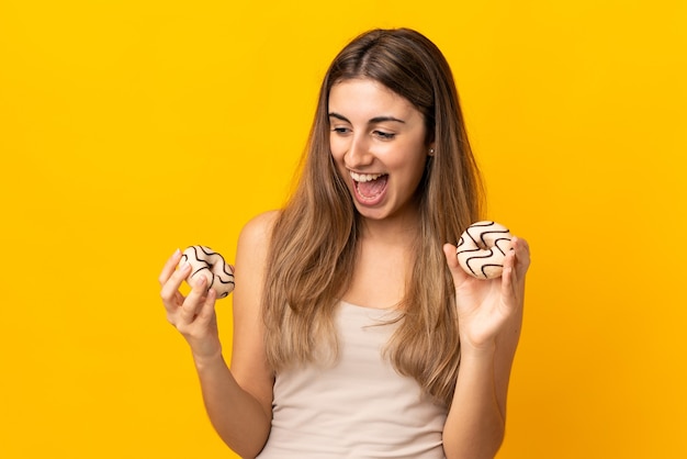 Młoda kobieta na pojedyncze żółte ściany trzymając pączki z happy wypowiedzi