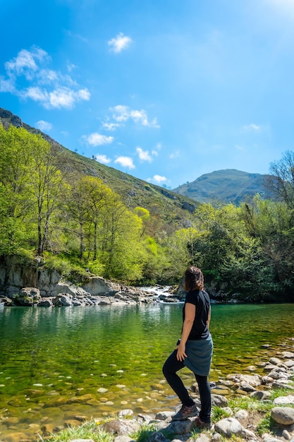 Młoda kobieta na wiosnę patrząca na jezioro Olla de San Vicente w pobliżu Cangas de Onis Asturias Hiszpania