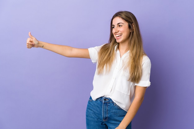 Młoda kobieta nad odosobnioną purpury ścianą daje aprobata gestowi
